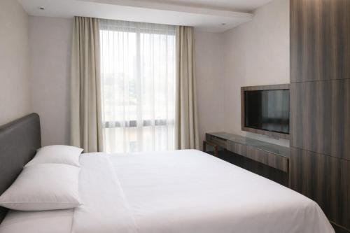 a hotel room with a bed and a television at Amrise Hotel Kitchener, Check In 9PM, Check Out 8AM in Singapore
