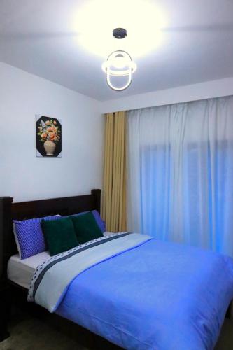 a bedroom with a bed with blue sheets and a light at GBSL Grand Villa in Nairobi