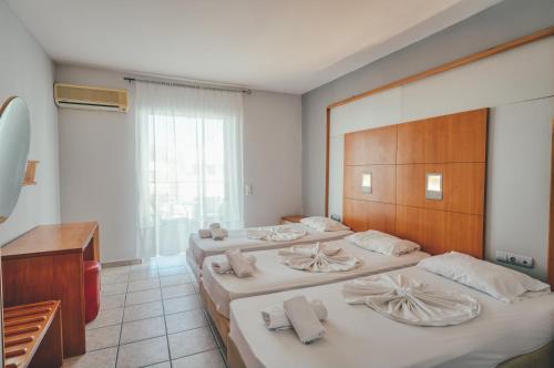 a hotel room with three beds with towels on them at Mojo Hotel Laganas Zante in Laganas