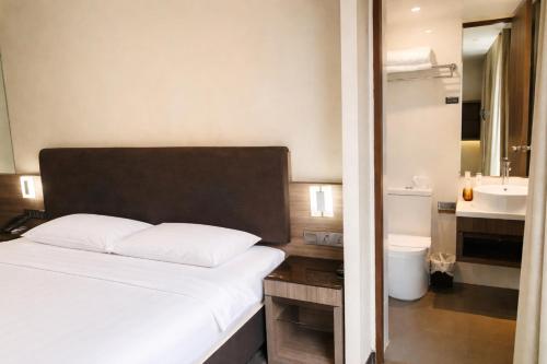 a bedroom with a white bed and a bathroom at Amrise Hotel Kitchener in Singapore
