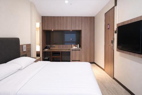 a hotel room with a bed and a television at Amrise Hotel Kitchener in Singapore