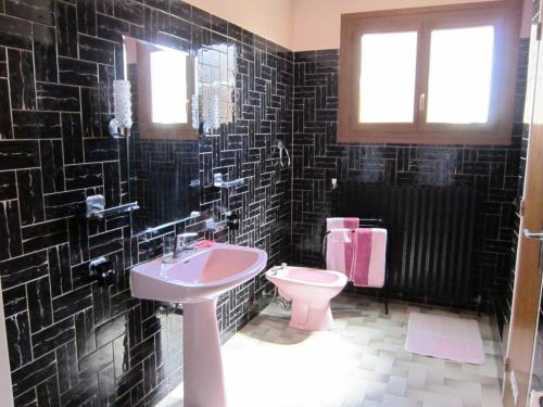 un baño con azulejos negros, lavabo e inodoro en Le gite ambert, en La Garde-Freinet
