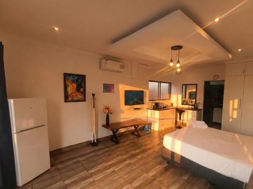 a bedroom with a bed and a desk and a refrigerator at Van Gogh - Zur See in Ballito