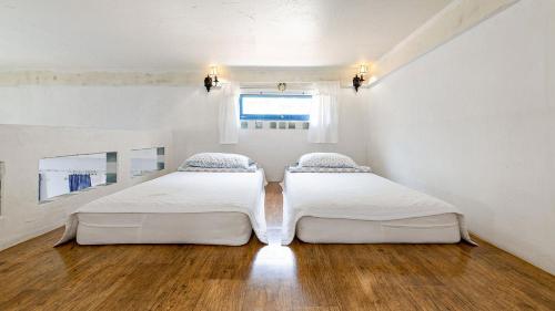two beds in a white room with a window at Ganghwa Picnic Pension in Incheon