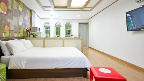 a bedroom with a bed and a red stool at Tongyoung Macaio Pension in Tongyeong