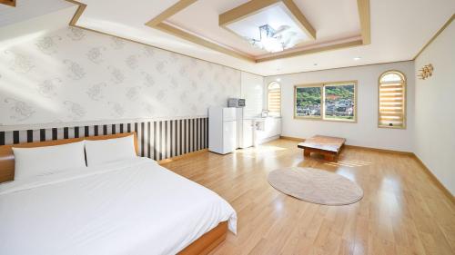 a bedroom with a large white bed and a kitchen at Tongyoung Macaio Pension in Tongyeong