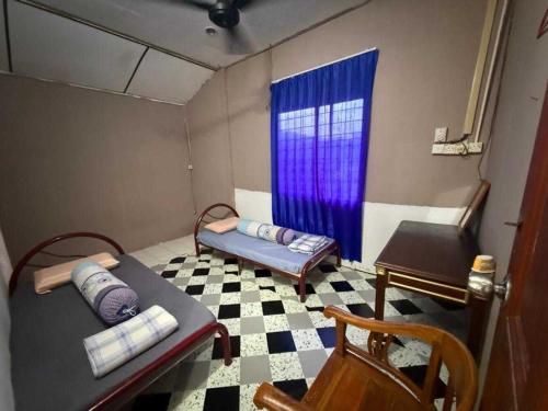 a small room with two beds and a blue curtain at OYO 91270 Sabsa Homestay in Kuching