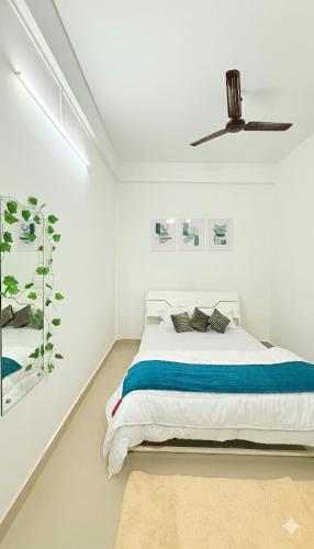 a white bedroom with a bed and a ceiling fan at Serenyaa in Dibrugarh