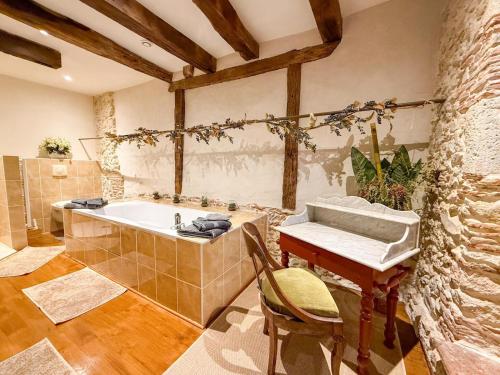a bathroom with a tub and a table and a sink at LE CLOS DU BENESTAR in Mauvezin-dʼArmagnac