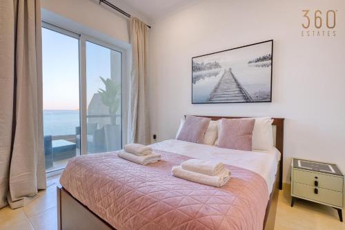 a bedroom with a bed with a view of the ocean at 2BR Seafront Elegance with Balcony & Sea Views by 360 Estates in St. Paul's Bay