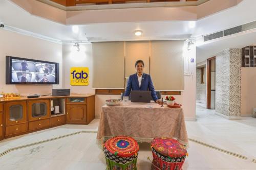 a man sitting at a table with a laptop at FabHotel Pink Cozzy in Jaipur