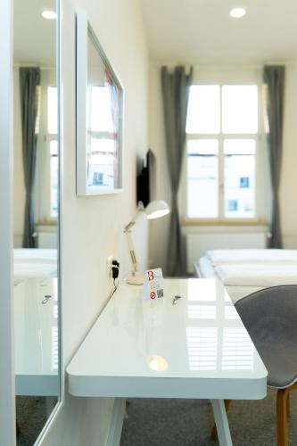 a white desk with a lamp and a bed in a room at Best Boarding House - Self Check-in - Kostenfreie Parkplätze in Hanau am Main