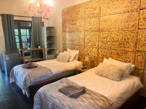 a room with two beds and a large wall at Karoozin Village in Oudtshoorn
