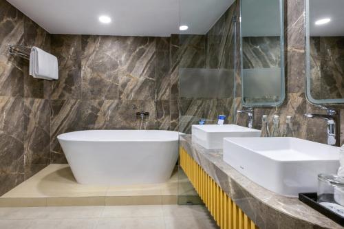 a bathroom with two sinks and a large tub at Aston Inn Cilacap in Cilacap