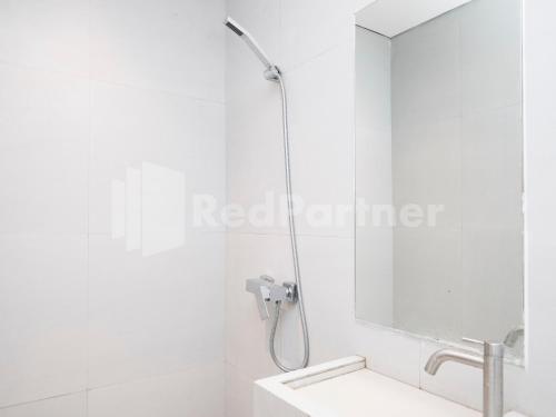 a shower in a white bathroom with a mirror at Mora Stay Demangan RedPartner in Yogyakarta