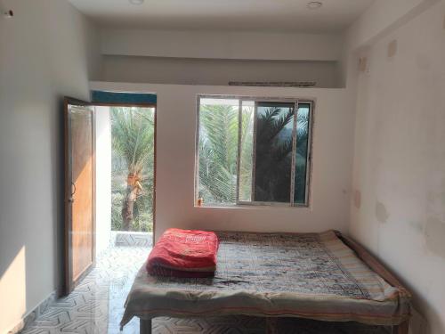 a bed in a room with two windows at Laxmi Narasimha Hotel in mayapur