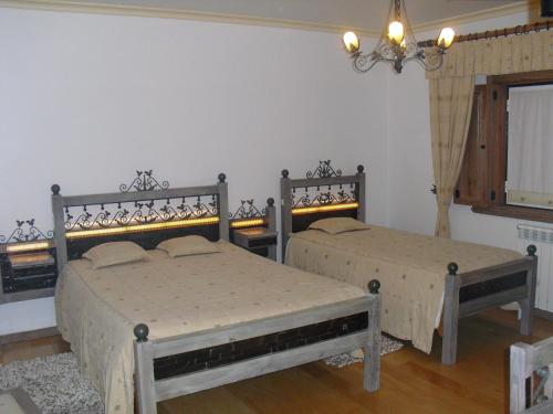 a bedroom with two beds and a chandelier at Descanso Serrano in Manteigas