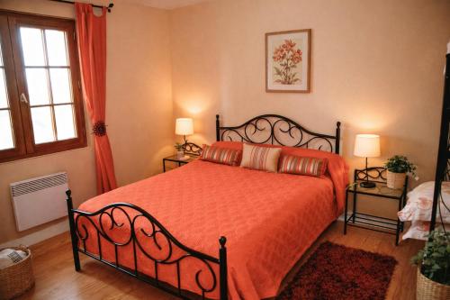 a bedroom with a bed with an orange bedspread at Maison Monbazillac avec piscine 2-4 pax in Monbazillac