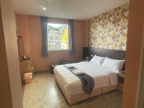 a bedroom with a large bed and a window at Night Sea Homestay in Jiufen