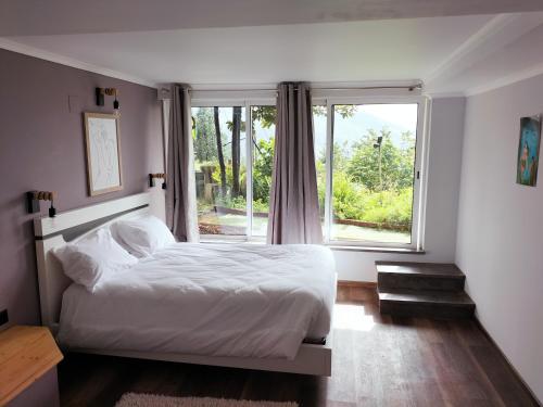 a bedroom with a bed and a large window at casa do campo in Machico
