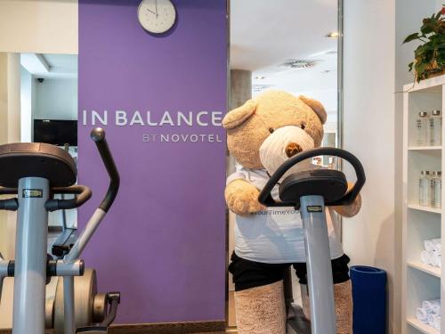 a teddy bear is standing next to two exercise bikes at Novotel Suites Malaga Centro in Málaga