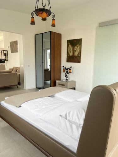 a large white bed in a bedroom with a living room at LOFT - Exclusive Penthousewohnung in Könen