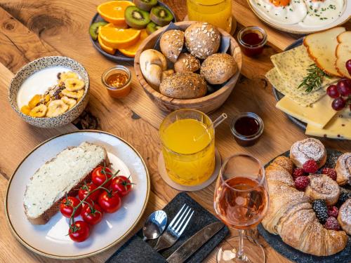 a wooden table topped with plates of food and glasses of wine at GRETI - Alpine Boutique Hotel mit Alpentherme Eintritt, reichhaltigem Frühstück, Sauna in Bad Hofgastein