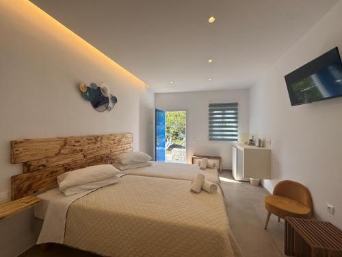 a bedroom with a large bed and a television at Anemos Hotel & Apartments in Ornos