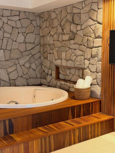 eine Badewanne in einem Badezimmer mit einer Steinwand in der Unterkunft Villa Sol e Mar in Maragogi