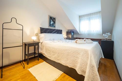 a bedroom with a large bed and a window at La Casina Azul de May By Silastur in San Juan de la Arena