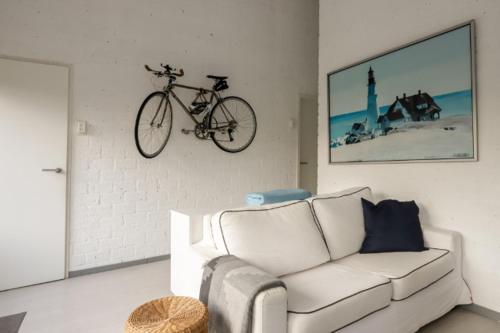 a living room with a couch and a bike hanging on the wall at Rekerlanden 90 in Schoorldam