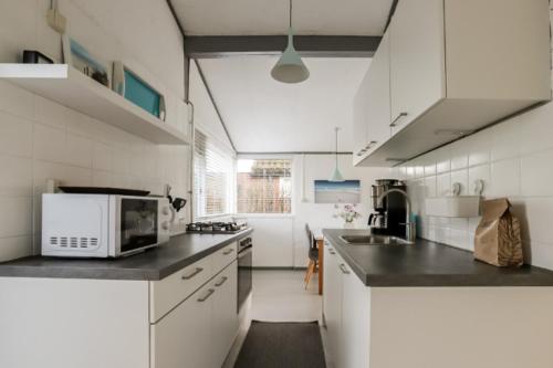 a kitchen with white cabinets and a microwave at Rekerlanden 90 in Schoorldam