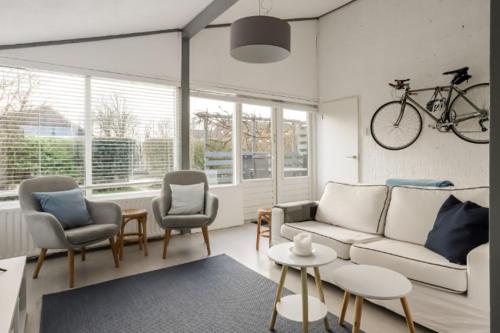 a living room with a couch and chairs and a bike on the wall at Rekerlanden 90 in Schoorldam