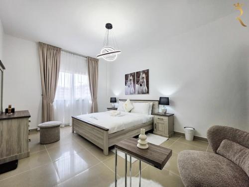 a bedroom with a bed and a couch and a table at Al Reef 1BR Retreat - Urban Stylish Stay in Abu Dhabi