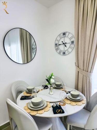a white table with chairs and a clock on the wall at Al Reef 1BR Retreat - Urban Stylish Stay in Abu Dhabi