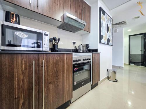 a kitchen with a stove and a microwave at Al Reef 1BR Retreat - Urban Stylish Stay in Abu Dhabi