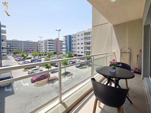 a balcony with a table and chairs and a view of a city at Al Reef 1BR Retreat - Urban Stylish Stay in Abu Dhabi