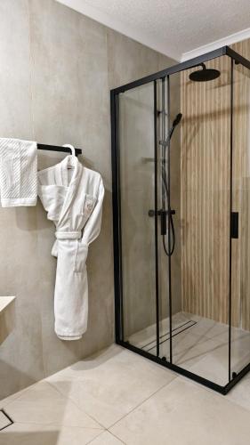 a shower with a glass door and a robe at Elegant Lux Hotel in Bansko