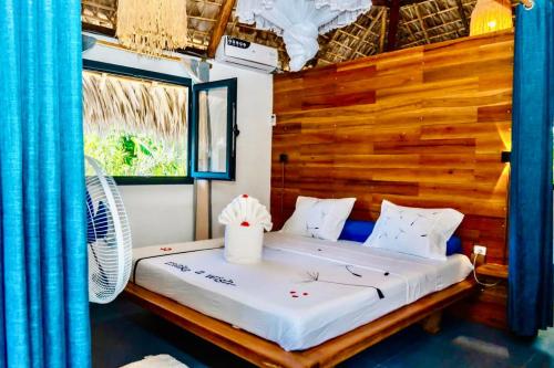 a bed in a room with a wooden wall at VILLA AMNESYA NOSY BE in Nosy Be
