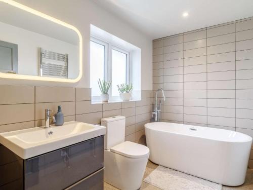a bathroom with a tub and a toilet and a sink at 3 Bed in Kings Lynn oc-82358 in Harpley