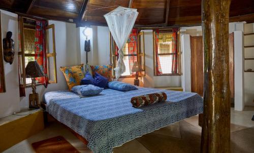 a bedroom with a bed with blue sheets and pillows at Ankobra Beach Resort in Axim