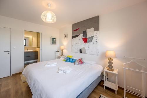 a bedroom with a large white bed and a bathroom at Le Clos Carnonen, villa avec piscine in Quessoy