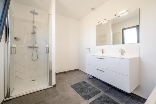 a white bathroom with a shower and a sink at Le Clos Carnonen, villa avec piscine in Quessoy