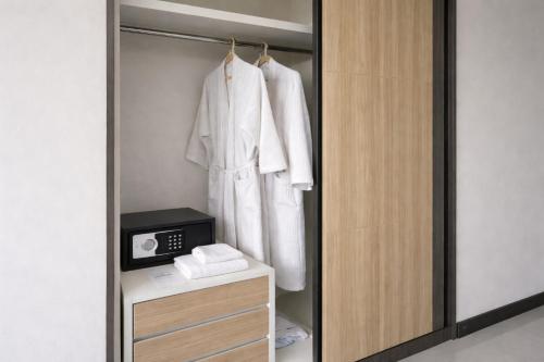 a walk in closet with white clothes and a microwave at Santosa Hotel & Welness Center in Kata Beach