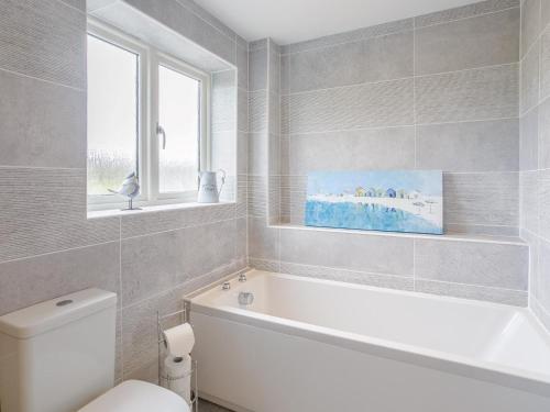 a bathroom with a tub and a toilet and a window at 5 Bed in Market Rasen oc-78678 in Tealby