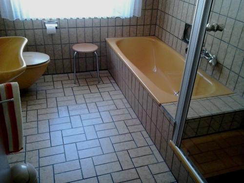 a bathroom with a tub and a stool and a toilet at Ferienwohnung Hunold in Marsberg