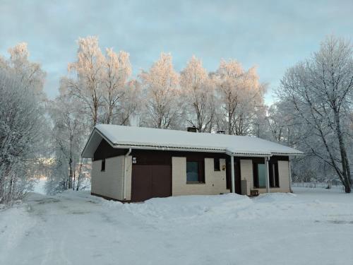 a small house covered in snow with trees in the background at Aurora riverside home in Rovaniemi