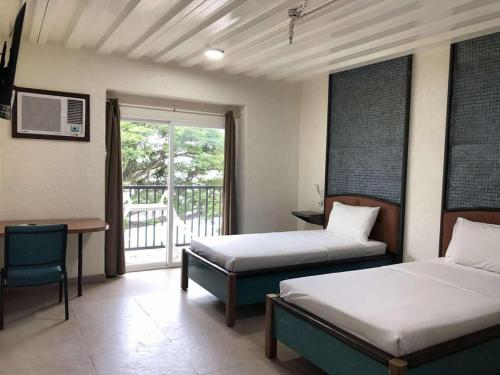 a bedroom with two beds and a desk and a window at Leuchtturm Resort in Boljoon