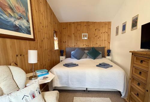 a bedroom with a bed and a couch and a television at Meads Cabin in Charmouth