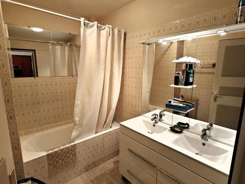 a bathroom with a sink and a bath tub and a mirror at Le Nid du Remblai in Les Sables-d'Olonne